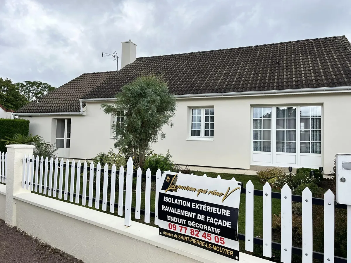 Panneau de chantier La Maison Qui Rénov devant une maison de la région